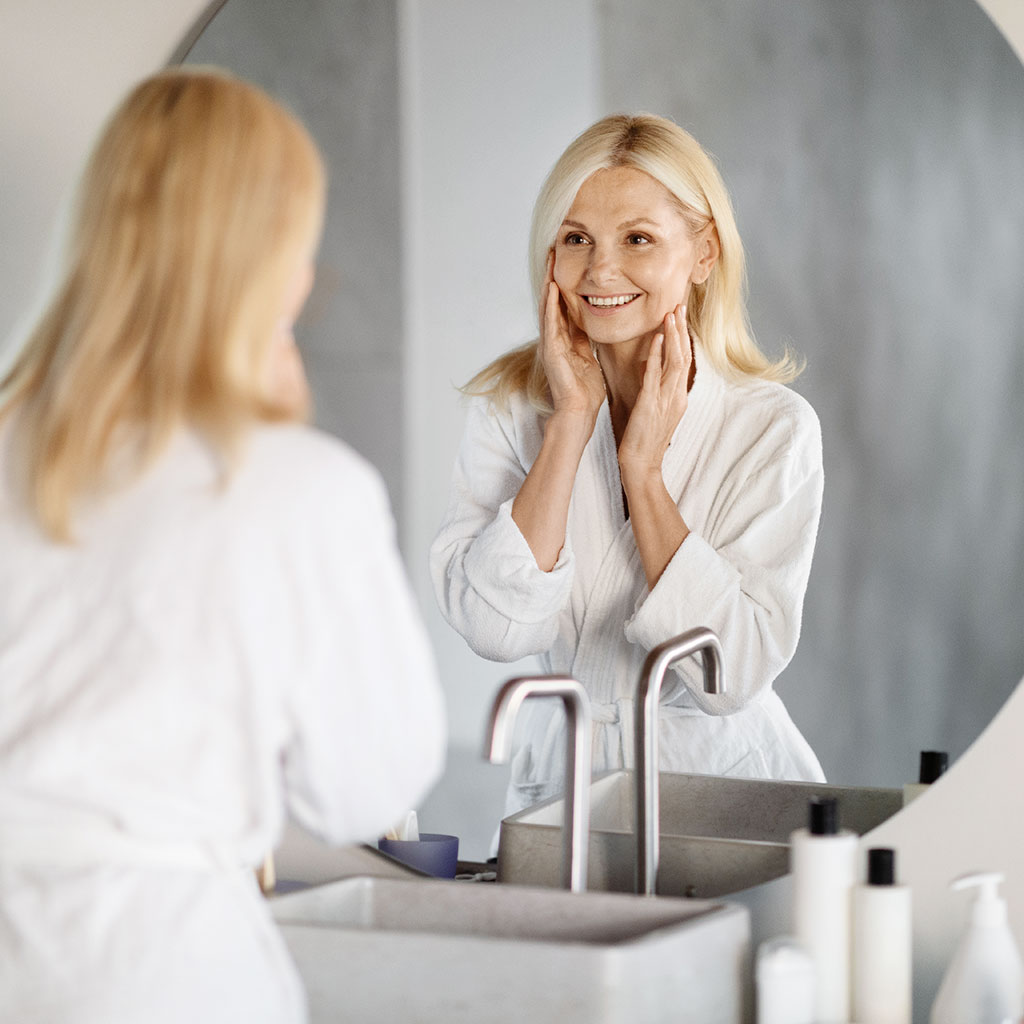 White woman checking skin in mirror